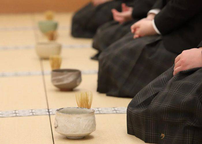 Guests in traditional Japanese kimono sitting in front of their matcha cups and tools.